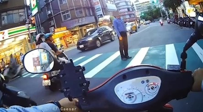 新北市永和區7月4日晚間18時許，有騎士左右竹林路上發現一名行人走在人行道上，但綠燈亮了行人卻不走，依舊站在人行道上，影響到下班車流，不管大家如何按喇叭他依舊不為所動，事後將影片PO網，警方竟說無法開罰，因為行人不能逕舉。（翻攝畫面）