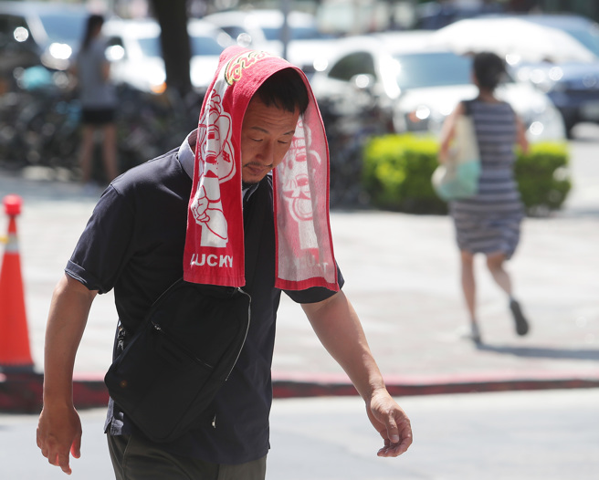 全台持续高温，路上行人耐不住紫外线，临时拿毛巾盖在头上防晒。（季志翔摄）