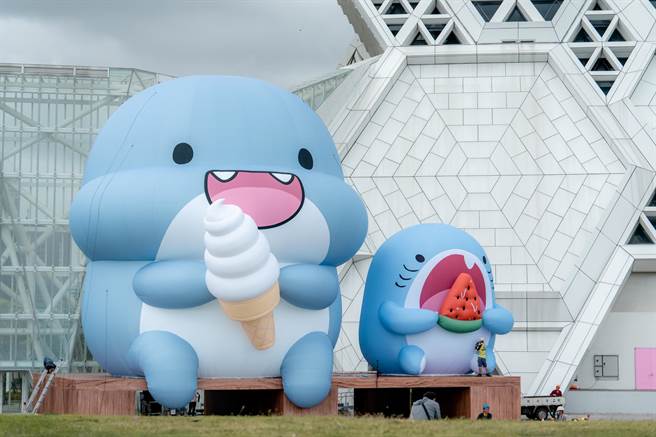 「胖鯊魚鯊西米」來了啦，在雪白高流音浪塔前，吃冰淇淋和西瓜的萌樣，實在很夏天。（擷取陳其邁臉書／柯宗緯高雄傳真）