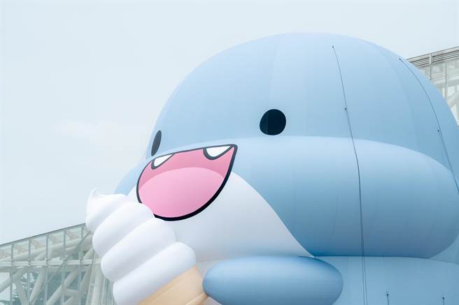 「胖鯊魚鯊西米」來了啦，在雪白高流音浪塔前，吃冰淇淋和西瓜的萌樣，實在很夏天。（擷取陳其邁臉書／柯宗緯高雄傳真）