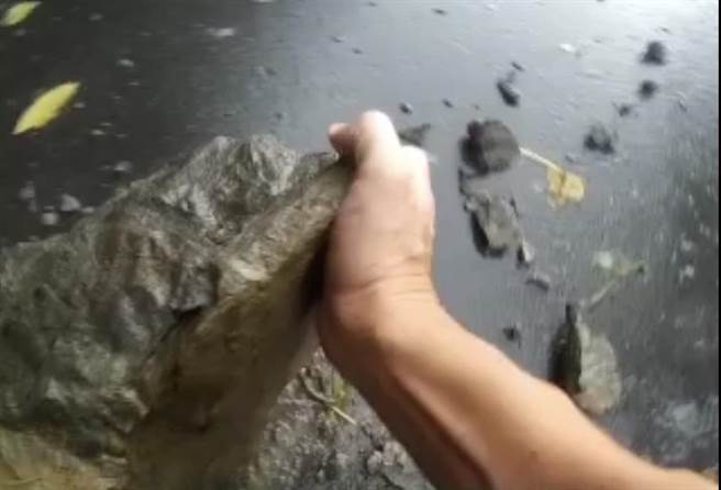 员警为求时效，在细雨中将大石头搬至路旁。（警方提供）