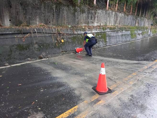 员警利用交通锥底座充当推土机，将路面泥土和碎石推至路旁，恢復道路顺畅。（警方提供）
