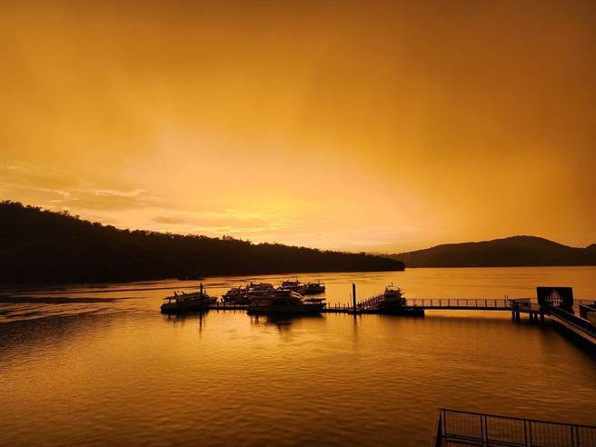 伊达邵码头的游客，因为太阳角度的关系，雨后只能看到被夕阳染成梦幻顏色的黄金湖。（日月潭风管处提供／杨静茹南投传真）