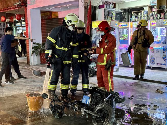 警消赶抵现场接手救援持续洒水降温，起火自燃的电动机车已烧得只剩骨架。(图／金门县消防局提供)