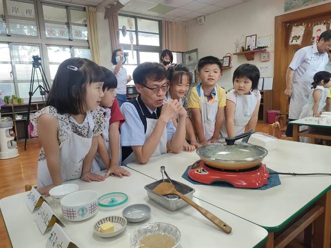 岸里国小附设幼儿园开办暑期延长照顾服务，台中市政府教育局长蒋伟民（左3）13日前往视察，孩童们于烹饪课进行爆米花，每位期待的看着锅内动静。（潘虹恩摄）