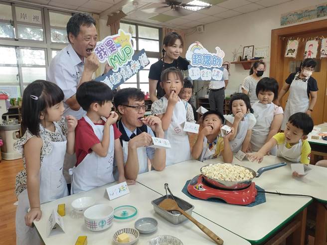 岸里国小附设幼儿园开办暑期延长照顾服务，台中市政府教育局长蒋伟民（前排左3）13日前往岸里国小附幼视察暑期上课情形，和孩童一起爆米花。（潘虹恩摄）