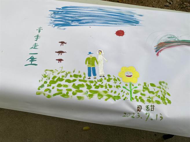 桃园大园横峰社区发展协会「一卷丹青千岁人生梦想彩画」活动，有长辈画出婚姻故事，并题字「牵手走一生」令人动容。（蔡明亘摄）