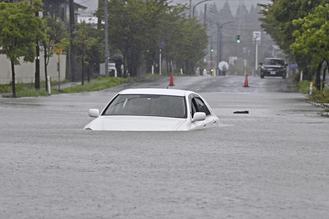 日本秋田縣降下破紀錄大雨，15日有汽車被困在淹水的道路中。（圖／美聯社）