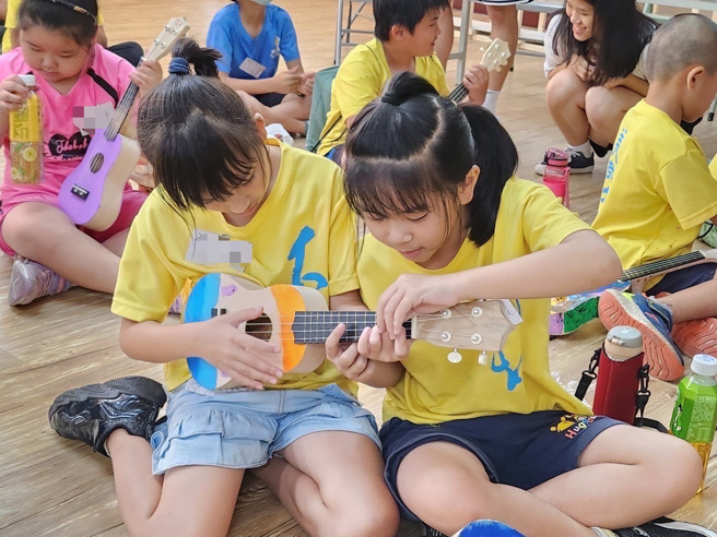 孩子们制作完自己的一把琴后，还跟姐姐学和弦。（音乐园丁团队提供）