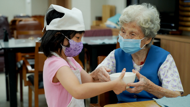 小朋友来到日照中心打工，帮爷爷奶奶摆放餐盘相当温馨。(图/林荷玉)