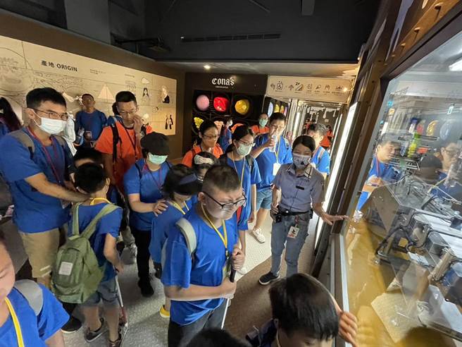 妮娜导览员带视障生触摸生产线的玻璃橱窗，让孩子得知巧克力在低温环境中才不会融化。（杨静茹摄）