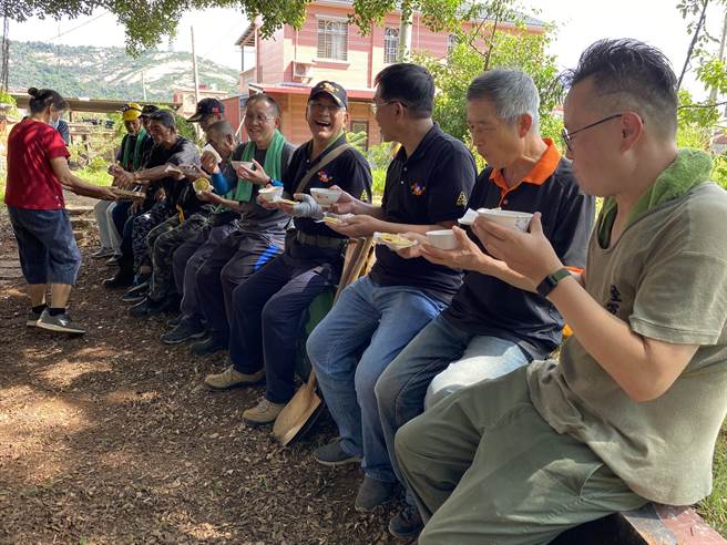 老兵们协助坑道清淤后，边品尝着「红龟粿」共聚大树底下话当年。(于家麒摄)