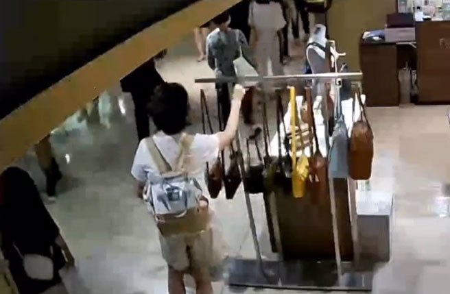 女窃贼直接拎走在挂在架上的背包。(影片翻拍)