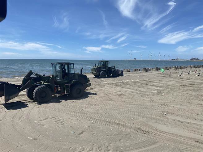 国军顶着烈日在沙滩上布署上百座消波块与钢刺猬等，工兵驾驶推土机来来回回穿梭，挖掘战车壕等，一旁还有国军安插诡雷、铁丝网等，场面壮观，层层防护保卫国家。(吴建辉摄)