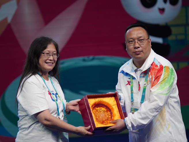 中华民国大专院校体育总会会长王淑音（左）致赠琉璃纪念品给成都世大运选手村村长黄建。（体育署提供／陈筱琳台北传真）