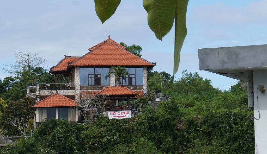 峇里島烏魯瓦圖居民在家掛上「拒絕Cube」海報，海報箭頭指向建地。（圖／中央社）
