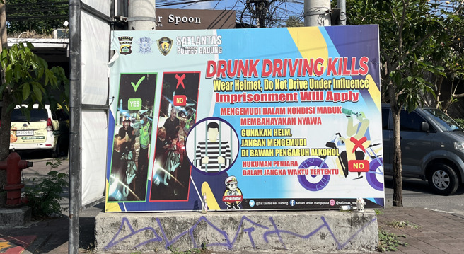 峇里岛警方在马路上设置看板，向外国游客宣导不酒驾、骑车必须戴安全帽。（图／中央社）