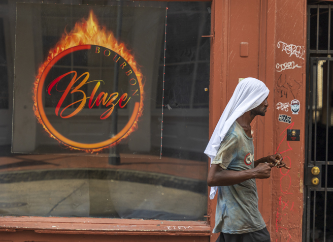 美国近日频遭热浪侵袭，南部路易斯安那州纽奥良居民周一（7月31日）披着降温毛巾上街。（美联社）