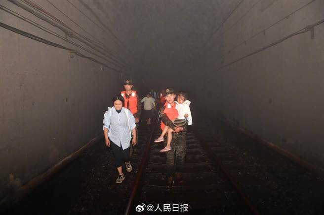 滞留2天2夜的K396乘客陆续脱困：这一刻，泪眼婆娑。 图为在武警队员护送下，第一批旅客开始向山下转移，连夜步行前往斜河涧车站。（人民日报）