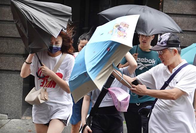 卡努颱风来袭，3日白天雨势不大，但风势忽强忽弱，突然而至的强风袭来让民眾措手不及，抵着雨伞御风前行。（姚志平摄）