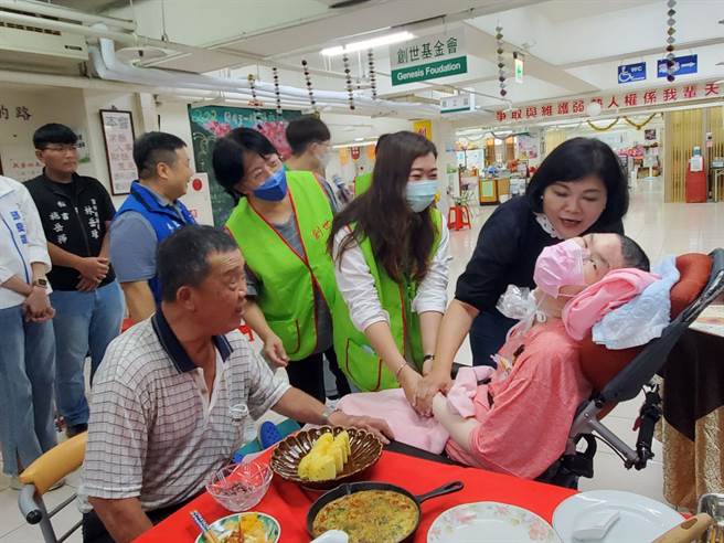 77岁林村寿老先生（左）接受主厨招待，县长张丽善（右）握着其植物人儿子林柯共的手打气。（周丽兰摄）