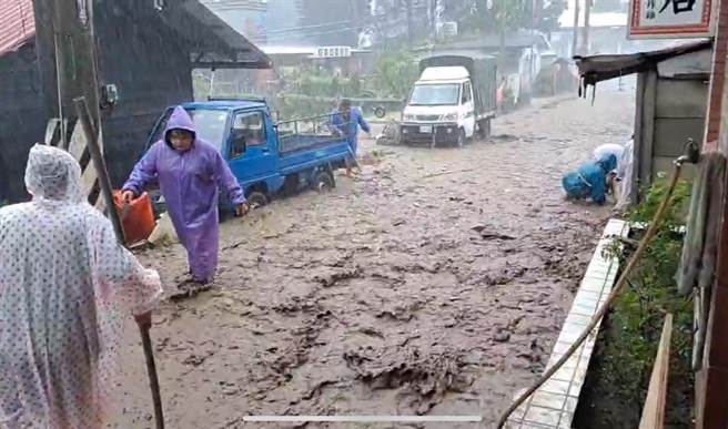 土石流沿着聚落道路往下冲刷，造成都达部落1邻、2邻的住户冒雨在家门口堆沙包防灾。（民眾提供／杨静茹南投传真）