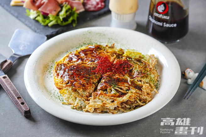 铁板臺上依序在高丽菜、柴鱼粉、特制鱿鱼风味天华、葱花、豆芽菜、猪肉、麵条、鸡蛋高高迭起，来一份初代广岛烧品嚐经典原味。(摄影/Carter)