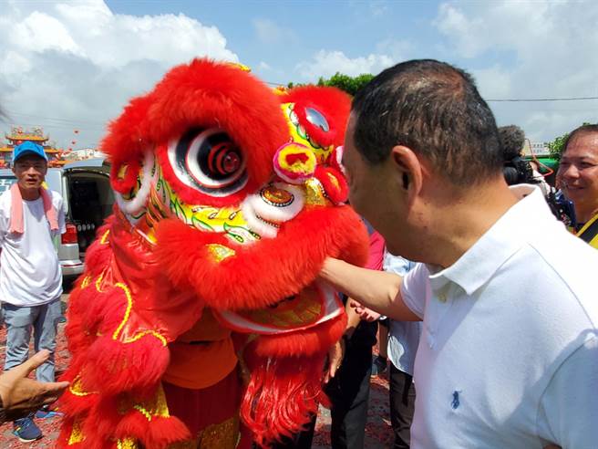 侯友宜到斗六市南圣宫向关圣帝君祝寿祈福，庙方安排2只醒狮表演助阵，舞弄红色醒狮的2个年轻人有一个不慎脚滑稍微跌倒，侯友宜亲自拿红包追，把红包塞入狮子嘴里安慰。（周丽兰摄）