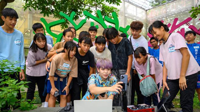 浪直播主「將軍」在亞泥生態園區開播，孩子們好奇圍觀，親眼看到直播主邊聊邊畫畫，回應訊息快速，直呼實在太厲害了。（圖片來源：浪凡基金會）