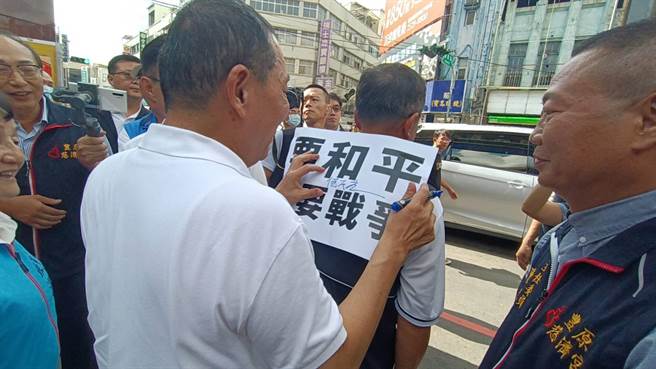 國民黨總統參選人侯友宜11日到豐原慈濟宮參拜，豐原區豐田里長劉瑞銓拿出「要和平，不要戰爭」標語給他簽名。（陳淑娥攝）