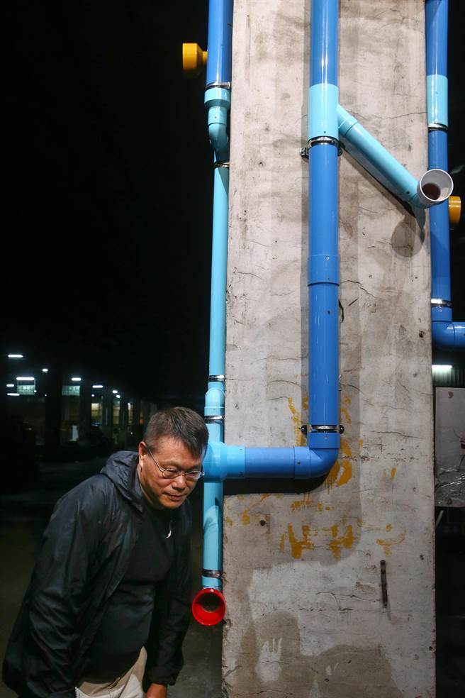蔡坤霖《台江声域》在台南市综合农产品批发市场内梁柱上用管线，将在地的四种地景声音融入于管路中。台艺大教授陈永贤正在聆听艺术家录制的声音。（邓博仁摄）