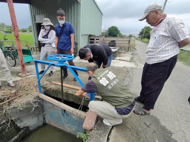 台中市乌日区庆光路116号旁农田灌溉沟渠侧岸剥离，民眾担心侧岸崩裂影响排水闸门开关，利用木棍与石块抵住双侧，防止侧岸倾斜挤压。（潘虹恩摄）