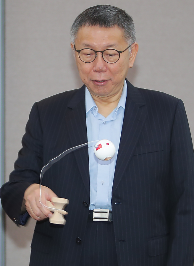 民眾黨主席柯文哲21日接見來訪的日本自民黨青年局海外研修團，研修團致贈繪有台日國旗的日本童玩「劍玉」，柯好奇地把玩了一下。（季志翔攝）