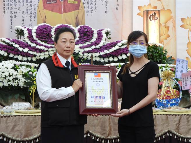 花莲县消防局特种搜救大队小队长蔡玺钧月初赴瑞士受训却猝死异乡，家属今在花莲市殡仪馆举办公祭，县长徐榛蔚（左）前往致哀，并颁授追晋令、消防荣誉章证书、奖牌等予代表接受的蔡妻（右）。（罗亦晽摄）