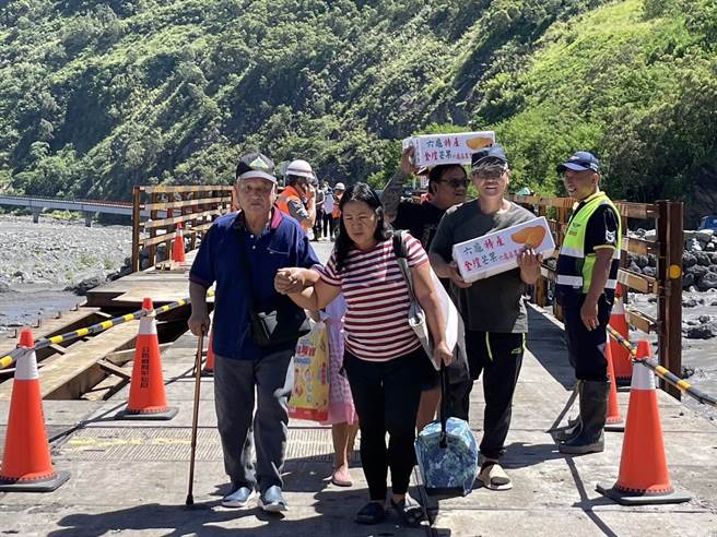 台20线明霸克露桥河床涵管便道22日晚间遭土石流覆盖，公路总局甲仙工务段今早6时进驻全吊式吊车，将修復中的钢便桥紧急搭设木工板，上午10时完成后已开放通行，有病患紧急下山就医，也有居民开心抱着金煌芒果，希望将採收的芒果赶紧运送出去。（高雄市原民会提供／林雅惠传真）