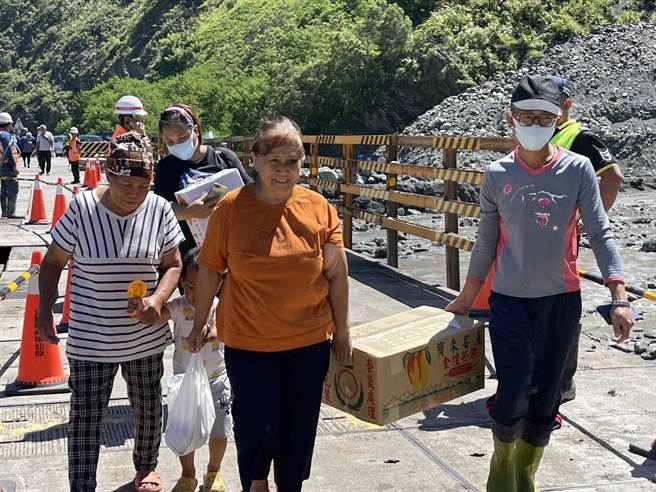 台20线明霸克露桥河床涵管便道22日晚间遭土石流覆盖，公路总局甲仙工务段今早6时进驻全吊式吊车，将修復中的钢便桥紧急搭设木工板，上午10时完成后已开放通行，有病患紧急下山就医，也有居民开心抱着金煌芒果，希望将採收的芒果赶紧运送出去。（高雄市原民会提供／林雅惠传真）