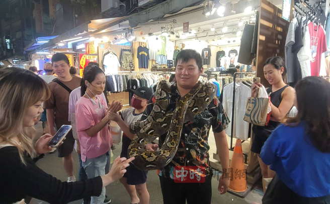 民眾见到蟒蛇逛大街，兴奋上前触摸、拍照。（游定刚拍摄）