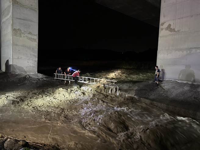 竹山消防分队利用搭设双节梯帮受困沙洲的两钓客跨越湍急溪流。（南投县消防局提供）