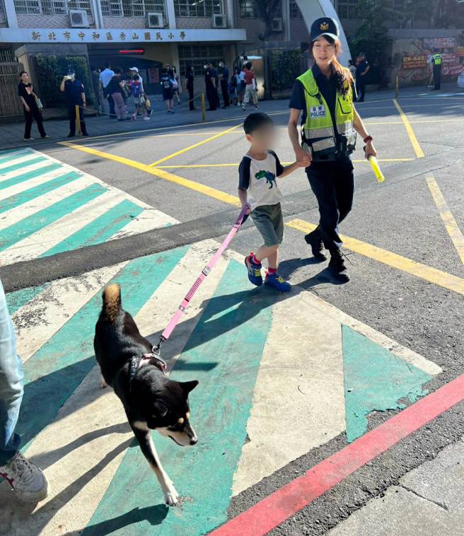 男童揮別緊張心情，與爸爸和自家柴柴揮手道別，牽著員警的手一同大步邁入校園。（照片 / 中和警提供）