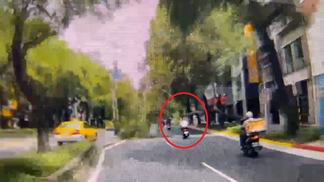 林姓騎士（紅圈處）遭路樹砸到，連人帶車重摔、血流滿面，送醫後傷重不治。（翻攝畫面）