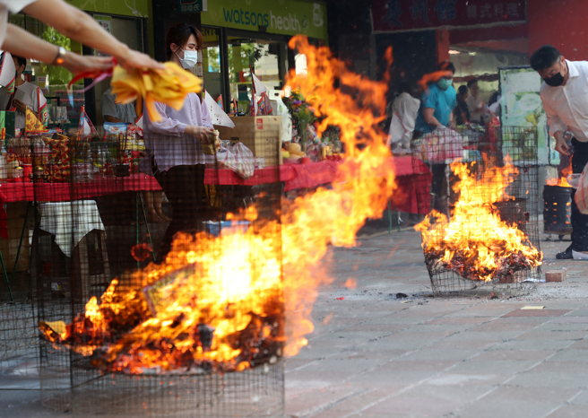  许多公司行号30日午后在公司大楼门口准备丰盛的供品，举行中元普渡，民眾虔诚祭拜，并烧纸钱让好兄弟领用。（刘宗龙摄）