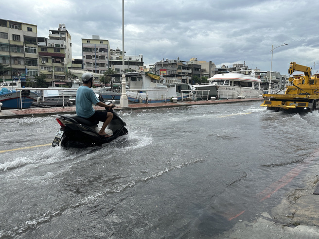 受年度大潮影响，高雄市鼓山区哨船街道路积水，骑士冒险涉水前行。（杨舒婷摄）