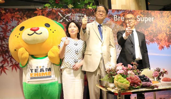 日台交流協會代表、微風超市副總（右），與吉祥物蜜柑狗合影。（微風提供）