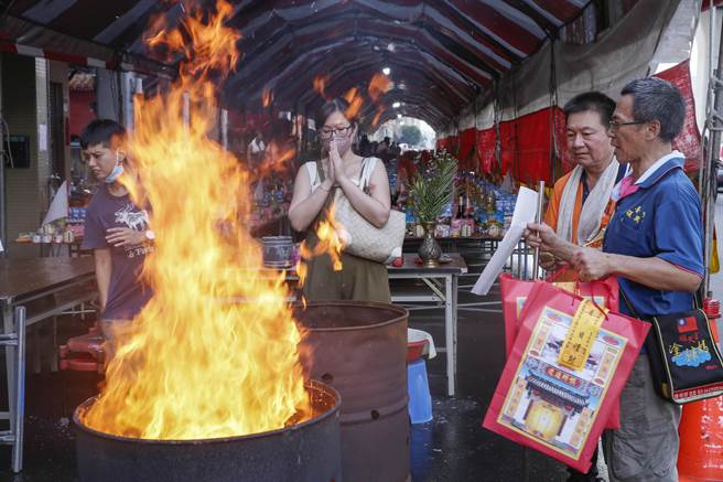 王芊妤（中）亲自带着特制的纸钱与纸糊毛孩用品，烧给已经去世4年的马尔济斯犬啾咪，当看着供品投入熊熊大火中，她在一旁跟着落泪。（黄子明摄）