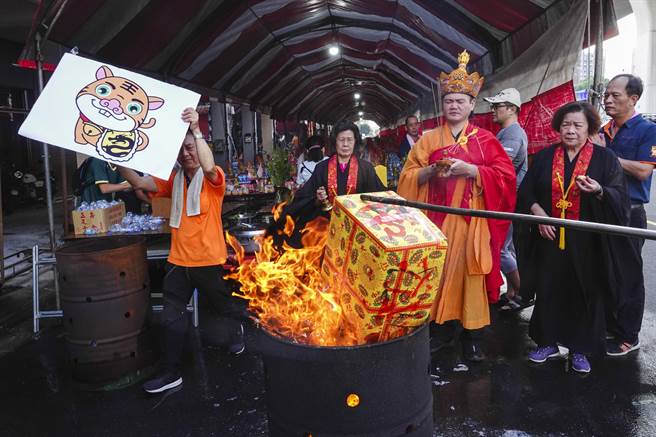 普渡仪式最后由道长率团到金炉旁念咒，志工拿着虎爷分身准备火化。（黄子明摄）