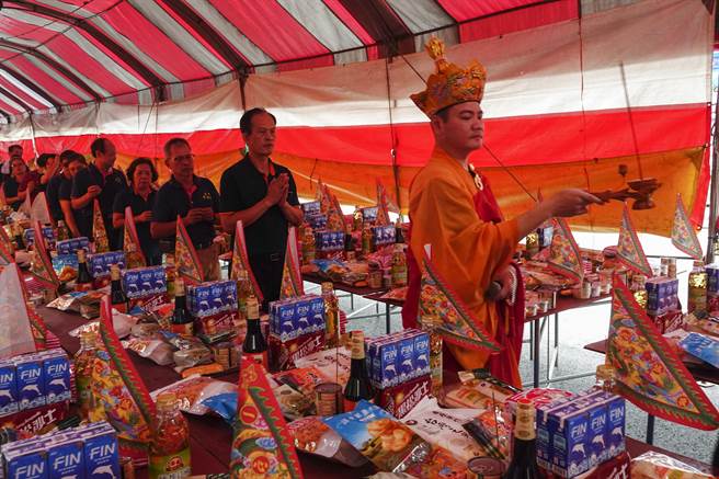 道长率诵经团成员与民眾环绕供桌洒净。（黄子明摄）