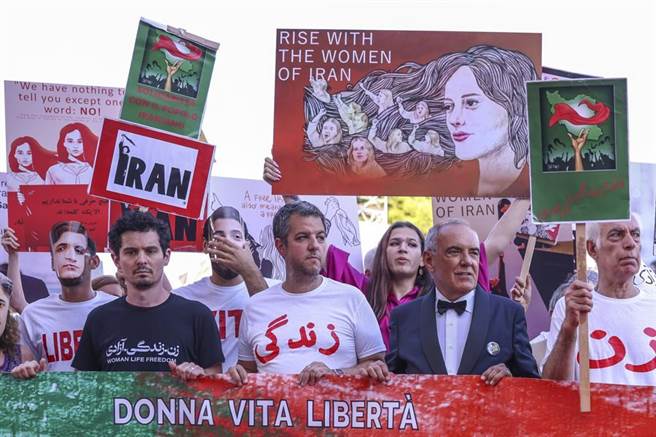 主竞赛评审团主席达米恩查泽雷（黑衣）跟着伊朗快闪人群斗士踏上威尼斯影展红毯。（图／美联社）