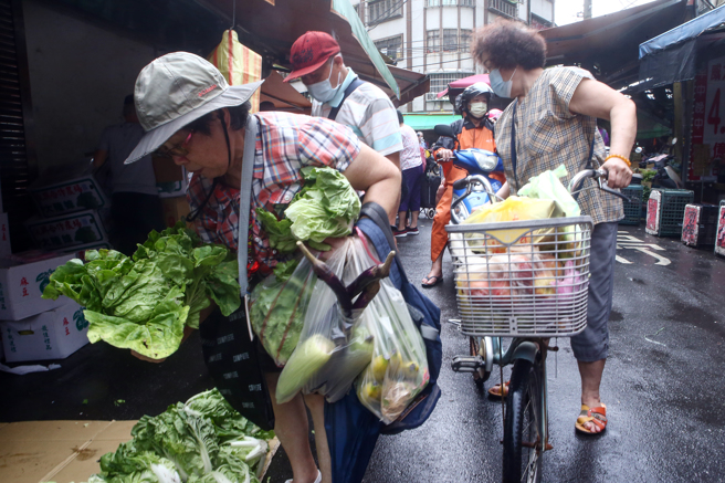  颱风海葵逐渐逼近台湾，影响部分蔬菜产量，价格也跟着水涨船高，涨多跌少，市场蔬果到货量少加上颱风来袭预期心理，不少民眾趁周日一早冒着风雨，到传统市场买菜，有许多民眾感受到，很多青菜、水果都变贵了。（邓博仁摄）