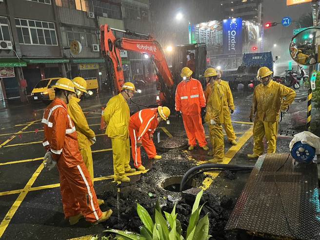 高雄市前金區大同二路發現手孔冒煙，台電員工連夜冒雨開孔，在雨勢中做低壓電纜更換。（台電提供／林瑞益高雄傳真）