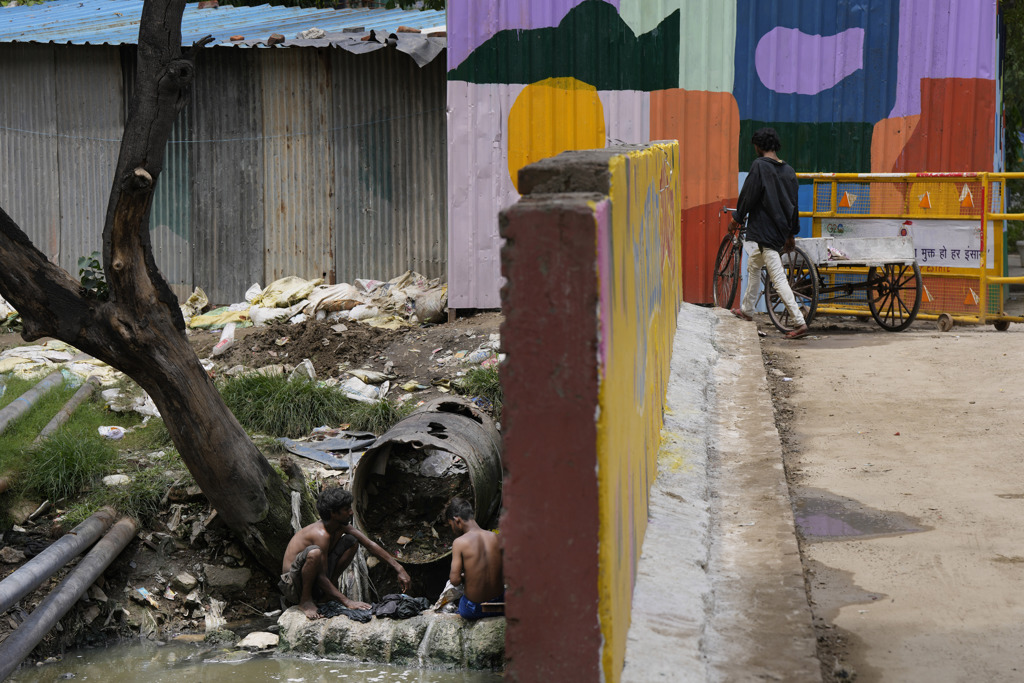 G20峰会即将于9日在新德里登场。市区一面新上漆的围墙后方日前有儿童正在污水排水口洗衣。（美联社）(photo:ChinaTimes)
